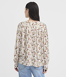 A woman in a floral blouse and jeans stands against a plain white background. carousel Product Image 3