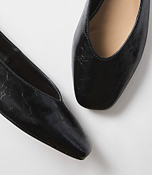Two black, square-toed flats with a slightly crinkled texture are positioned on a plain white background. carousel Product Image 2