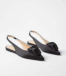 A pair of black satin slingback flats with a rose embellishment on the toe rest on a plain white background. carousel Product Image 1
