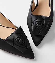 Two black satin pointed-toe heels with rose embellishments are displayed against a plain white background. carousel Product Image 2