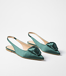 A pair of emerald green satin slingback flats with rose embellishments are displayed against a plain white background. carousel Product Image 1
