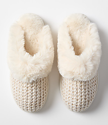 A pair of cozy, cream-colored slippers with knitted uppers and fluffy lining rest on a plain white background. carousel Product Image 3