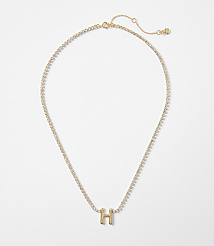 A gold necklace with a sparkling chain and a gold letter "H" pendant rests against a plain white background. carousel Product Image 1