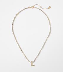 A delicate gold necklace with a sparkling chain and a single letter "L" charm rests on a plain white background. carousel Product Image 1