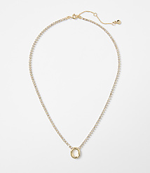 A delicate gold necklace with a circular pendant, adorned with small clear stones, rests against a plain white background. carousel Product Image 1