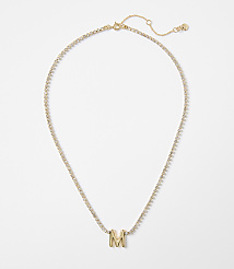 A gold necklace with a diamond-encrusted chain and a prominent "M" pendant rests on a plain white background. carousel Product Image 1