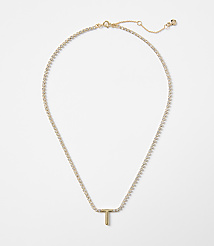 A delicate gold chain with a sparkling "T" pendant rests against a plain white background. carousel Product Image 1