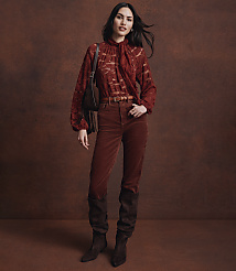 A woman in a rust-colored lace blouse and corduroy pants stands against a textured brown backdrop. carousel Product Image 3
