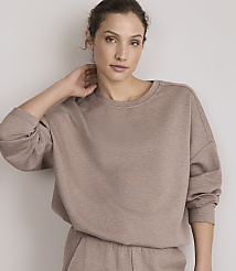 A woman in a taupe sweatshirt and matching pants poses against a plain, light-colored wall. carousel Product Image 1