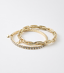 Two gold bracelets, one with a chunky chain design and the other with a band of small rhinestones, rest on a plain white background. carousel Product Image 1