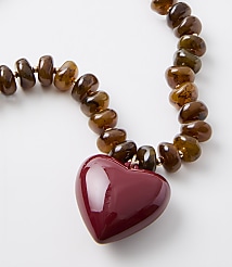 A glossy red heart pendant hangs from a strand of translucent brown beads against a plain white background. carousel Product Image 2
