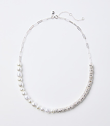 A delicate silver necklace with a chain of pearls on the left and a band of sparkling rhinestones on the right rests on a plain white background. carousel Product Image 1