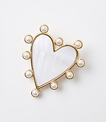 A white, heart-shaped brooch with a mother-of-pearl inlay and a border of small pearls sits against a plain white background. carousel Product Image 1