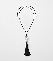 A black tassel necklace with a clear gem and pearl hangs against a plain white background. carousel Product Image 1