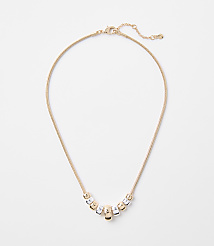 A delicate gold chain necklace with a series of alternating gold and silver cylindrical beads rests on a plain white background. carousel Product Image 1