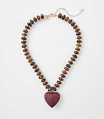 A beaded necklace with a heart-shaped pendant rests on a plain white background. carousel Product Image 1