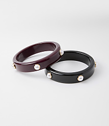 Two chunky bangles, one deep red and the other black, are adorned with small pearls and gold accents, set against a plain white background. carousel Product Image 1