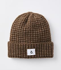 A brown waffle-knit beanie with a white tag featuring a black ampersand sits against a plain white background. carousel Product Image 1