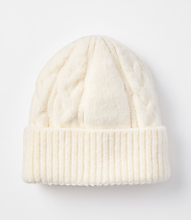 A cream-colored cable-knit beanie with a ribbed cuff rests on a plain white background. carousel Product Image 1