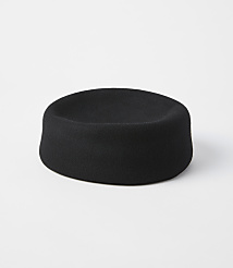 A black felt hat with a shallow crown sits on a white surface against a plain white background. carousel Product Image 1