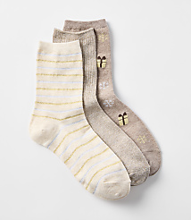 Three cozy socks, one with gold and blue stripes and two with a festive gift pattern, are arranged against a plain white background. carousel Product Image 2