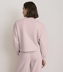 A woman in a pale pink sweatshirt and pants stands against a plain, light-colored background. carousel Product Image 3