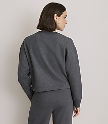 A woman in a dark grey sweatshirt and matching pants stands with her back to the viewer against a plain grey background. carousel Product Image 3