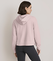 A woman in a pink hoodie and dark leggings stands against a plain, light gray background. carousel Product Image 3