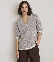 A woman in a speckled v-neck sweater and brown pants stands against a plain, light gray background. carousel Product Image 1