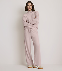 A woman in a pink ribbed loungewear set stands with her arms crossed against a plain, light-colored background. carousel Product Image 1