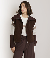A woman in a brown fuzzy vest and striped sweater stands against a plain white background. carousel Product Image 1