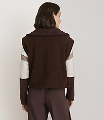 A woman in a brown fuzzy jacket with striped sleeves stands against a plain white background. carousel Product Image 3
