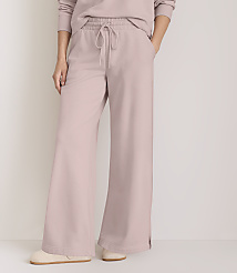 A person stands in light pink wide-leg sweatpants and slippers against a plain white background. carousel Product Image 2