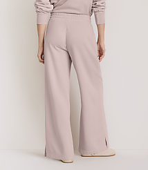 A person wearing light pink wide-leg sweatpants with side slits stands on a light-colored floor against a plain white background. carousel Product Image 3