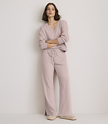A woman in a light pink loungewear set stands with her arms crossed against a plain, light-colored wall. carousel Product Image 1