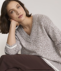 A woman in a speckled v-neck sweater rests her head on her hand against a plain background. carousel Product Image 2
