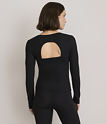 A woman in a black long-sleeved top with a cutout back and black leggings stands against a plain gray background. carousel Product Image 3