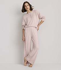 A woman in pink pajamas stands against a plain, light gray background. carousel Product Image 1