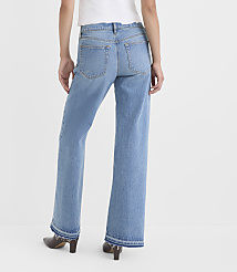A person wearing light-wash flared jeans with frayed hems stands against a plain white background. carousel Product Image 3