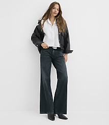 A woman in a white shirt, black jacket, and wide-leg jeans stands against a plain white background. carousel Product Image 1