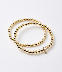 A gold beaded bracelet with a diamond-encrusted "P" charm is laid out on a white background. carousel Product Image 1