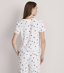 A woman in a white t-shirt and pants with a small red and green butterfly pattern stands against a plain white background. carousel Product Image 3