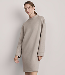 A woman in a beige sweatshirt dress stands against a plain, light gray background. carousel Product Image 2