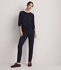 A woman in navy loungewear stands against a plain, light-colored wall. carousel Product Image 2