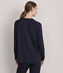 A woman in a dark blue sweater and pants stands with her back to the viewer against a plain, light gray background. carousel Product Image 3