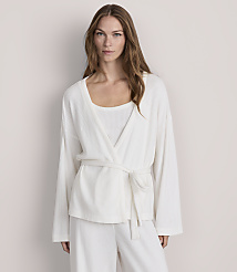 A woman in a white ribbed robe and matching pants stands against a plain, light-colored background. carousel Product Image 2
