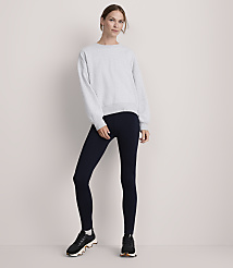 A woman in a light gray sweatshirt and dark blue leggings stands against a plain, light-colored background. carousel Product Image 1