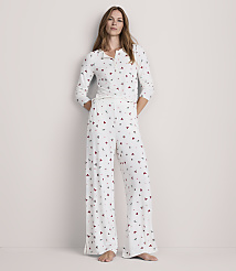 A woman stands in a white pajama set with a subtle heart pattern, against a plain, light-colored background. carousel Product Image 1