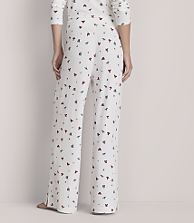 A person stands in white pajamas with a red and green holly pattern, against a plain, light-colored background. carousel Product Image 3