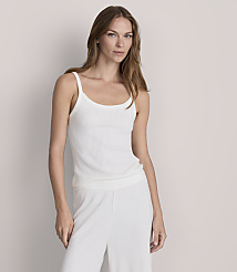 A woman in a white ribbed tank top and matching pants stands against a plain, light gray background. carousel Product Image 1
